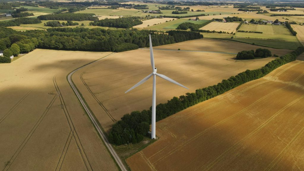 Aerial view of a wind turbine amidst lush fields in Torring, Denmark.